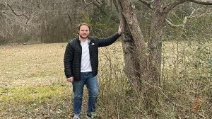 Jacob Johnson stands next to a tree