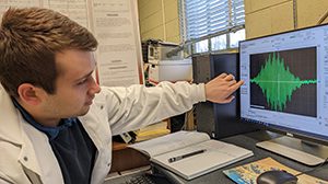 Taylor McGee pointing to research on the computer screen