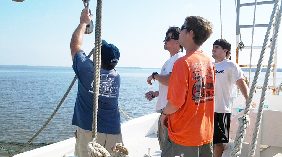 students hauling in a shrimp line on a boat in the ocean