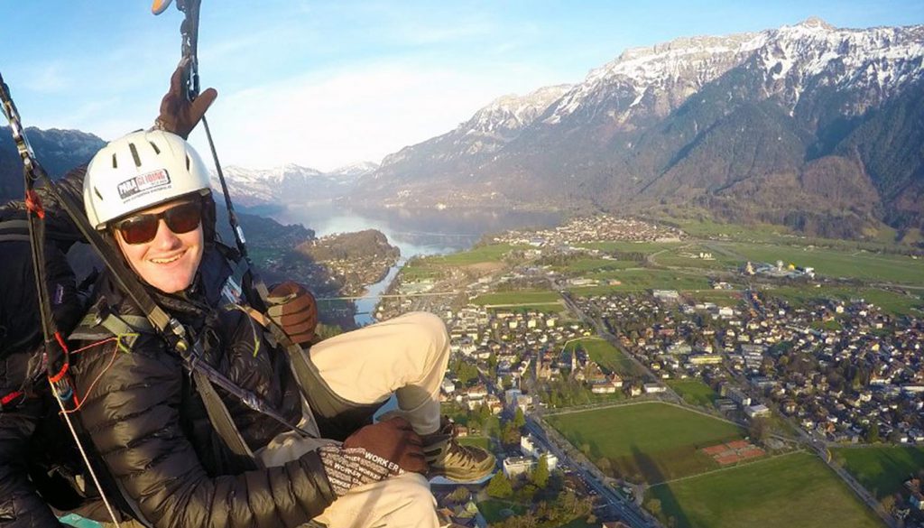 Student paragliding with a view of a mountain peak and a city below